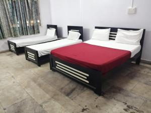 three beds in a room with red blanket at HOTEL BPR Residency in Hyderabad