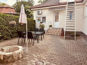 a patio with a table and an umbrella and a ladder at Thermal Garden Weninger Apartmanok in Kiskunhalas