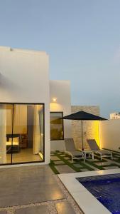 a house with a patio with chairs and an umbrella at Rove Chalet in á¸¨arÄdÄ«