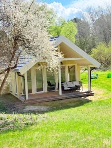 a yellow house with a deck and a tree at Papės Perlas in Pape