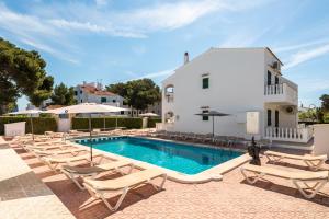 a villa with a swimming pool and lounge chairs at Apartamentos Mar Blanca by Mauter Villas in Cala Blanca
