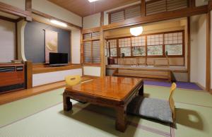 a living room with a table and a television at Takaragawa Onsen Ousenkaku in Minakami