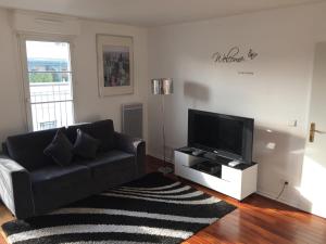 a living room with a black couch and a flat screen tv at Appartement near Disneyland in Serris