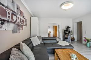a living room with a black leather couch and a wooden table at Ferienwohnung Sauerland an der Ruhr in Olsberg
