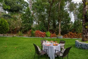 a table in a garden with a white table cloth at Avocado Cottages by Alaya Stays, Coorg in Suntikoppa +86 photos