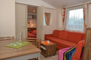 a living room with a red couch and a table at Camping Le Puits Rochais in Les Sables-d'Olonne