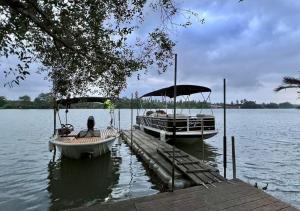 Zwei Boote liegen an einem Steg an einem See. in der Unterkunft Amphawa Hideaway in Amphawa + 21 Fotos