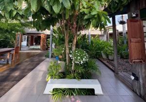 ein Garten mit einem Baum und einer Bank in der Unterkunft Amphawa Hideaway in Amphawa