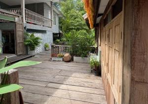 eine Veranda eines Hauses mit Holztür und Pflanzen in der Unterkunft Amphawa Hideaway in Amphawa