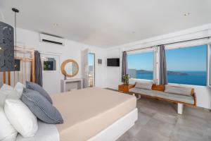 a white bedroom with a large bed and a couch at Gizis Cliffside Suites in Imerovigli