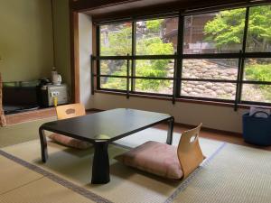 a coffee table and a chair in a room with a window at Takaragawa Onsen Ousenkaku in Minakami