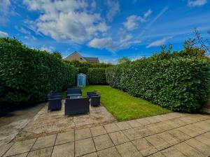 a yard with two chairs and a hedge at 6 Bedroom Spacious villa, Free Parking in Byfleet