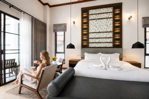 a woman sitting in a chair next to a bed at Wonderland Resort Chiangmai in Chiang Mai +47 photos