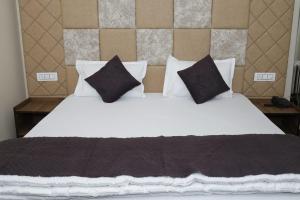 a bedroom with a bed with black and white pillows at Doon Sanskaram Hotel in Chūharpur