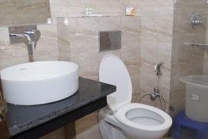 a bathroom with a white toilet and a sink at Doon Sanskaram Hotel in Chūharpur +3 photos