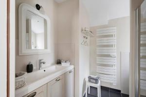 a white bathroom with a sink and a mirror at Rêves d'Emeraude in Cancale