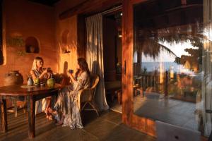 two women sitting at a table in a room with a window at Palm Grove Beach Resort in Mandrem
