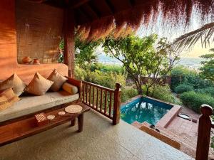 a living room with a couch and a swimming pool at Palm Grove Beach Resort in Mandrem