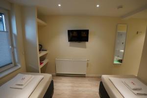 two beds in a room with a tv on the wall at Pension Dortmund Messe in Dortmund +95 photos