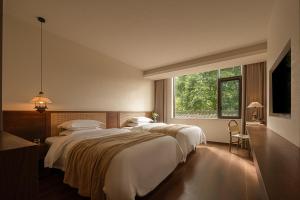 a bedroom with three beds and a large window at Liaoxin Valley Forest Hotel in Jiezi Ancient Town