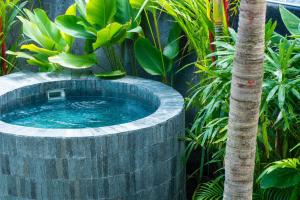 a circular plunge pool in a garden with a palm tree at Watermark Hotel & Spa Bali in Jimbaran