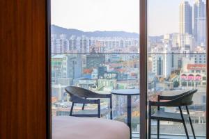 a room with two chairs and a table and a window at Hotel Editions Mokpo in Mokpo