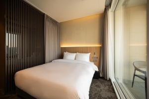 a large white bed in a room with a window at Hotel Editions Mokpo in Mokpo