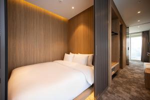 a bedroom with a large white bed and a mirror at Hotel Editions Mokpo in Mokpo