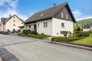 a white house with a black roof on a street at Ferienwohnung Niemeier in Brilon