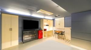 a living room with a television and a kitchen with a table at 747 Motel in Gimcheon