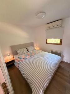 a bedroom with a bed with striped sheets and a window at Panonska hiška - Panonian nest - vključeni 2 kopalni karti za Terme3000 in Moravske-Toplice +11 photos
