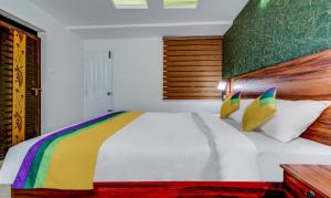 a bedroom with a white bed with a rainbow blanket at Itsy Hotels Dew Dreams in Cochin