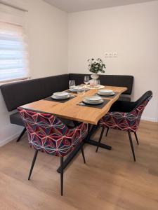 a wooden table with two chairs with plates and wine glasses at Panonska hiška - Panonian nest - vključeni 2 kopalni karti za Terme3000 in Moravske-Toplice