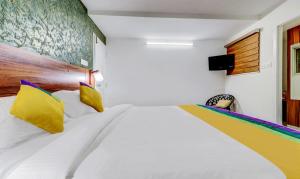 a bedroom with a large white bed with yellow pillows at Itsy Hotels Dew Dreams in Cochin