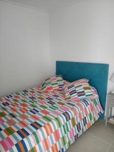 a bed with a colorful comforter and two pillows at Beau séjour in Pedreguer