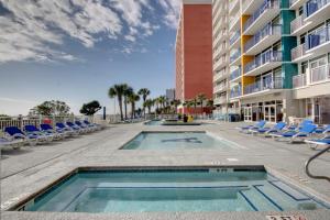 an outdoor swimming pool with chairs and a building at Hosteeva Atlantica Oceanfront Condo in Myrtle Beach