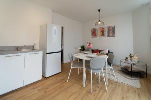 a kitchen with a white refrigerator and a table with chairs at T2 moderne Mon Toit in Mont-de-Marsan