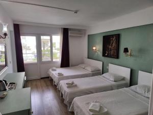 three beds in a room with green walls at Datça Stayinn Otel in Datca