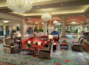 a lobby with a red couch and chairs and chandeliers at Omni Shoreham Hotel Washington DC in Washington, D.C.