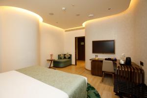 a hotel room with a bed and a desk and a television at 080 Transit Hotel, T2 in Bangalore