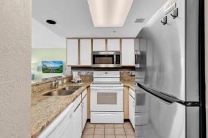 a kitchen with a sink and a refrigerator at Hosteeva Atlantica Oceanfront Condo in Myrtle Beach +32 photos