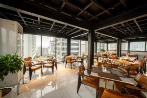 a restaurant with wooden tables and chairs and windows at WYNNE Hotel Nha Trang in Nha Trang