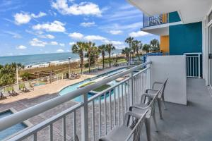 a balcony with chairs and a swimming pool and the beach at Hosteeva Atlantica Oceanfront Condo in Myrtle Beach