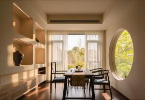 a dining room with a table and chairs and a window at Liaoxin Valley Forest Hotel in Jiezi Ancient Town
