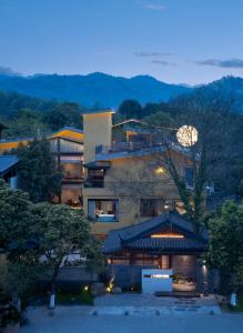 a large building with a tree in front of it at Liaoxin Valley Forest Hotel in Jiezi Ancient Town