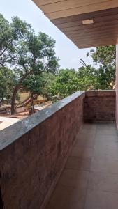an outdoor balcony with a stone wall and trees at Hotel M N Matheran in Matheran