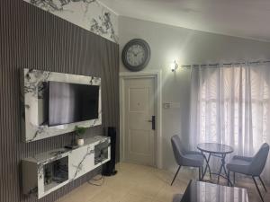 a living room with a tv and a table and a clock at Trelawnys Bliss Escape in Spring Rises