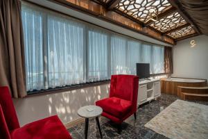 a room with a red chair and a desk and window at Ween Otel in Trabzon