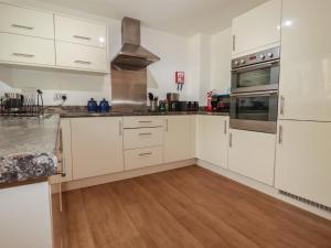 a kitchen with white cabinets and a wooden floor at Treveline in Bodmin