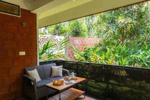 a chair and a table on a balcony at Avocado Cottages by Alaya Stays, Coorg in Suntikoppa
